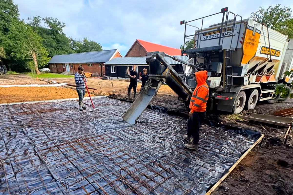Concrete being poured from a volumetric mixer onto the reinforced base